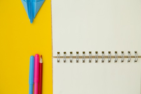 Write down creative ideas. An opened blank notebook and colored markers and pencils on a yellow background. Space for your text or product display.の写真素材