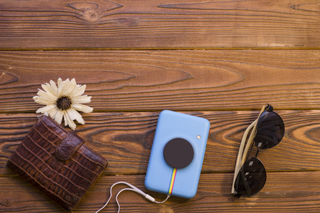 Packing luggage for a trip. A leather wallet, a flower, camera and black sunglasses on a rustic wooden background. Space for a text or product display, top view.の写真素材