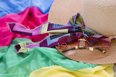 A straw hat and sunglasses on a colored fabric background. Tourism concept background, top view.の写真素材