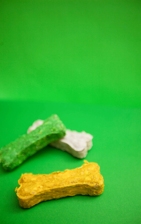 Colored bone snacks for dogs on a bright one-color green background. Pet care and veterinary concept. Spase for your text or image.の写真素材