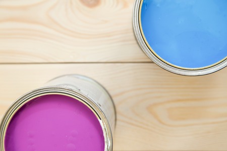 Painting a house. Tin cans of blue and fuchsia oil paint on a light uncolored wooden background. Close up. Top view. Space for your text or pruduct display.の写真素材