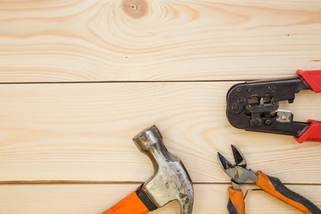 Repairing and construction concept. A set of repair tools- a hammer and pilers on a light uncolored wooden background. Top view. Space for your text or pruduct display.の写真素材