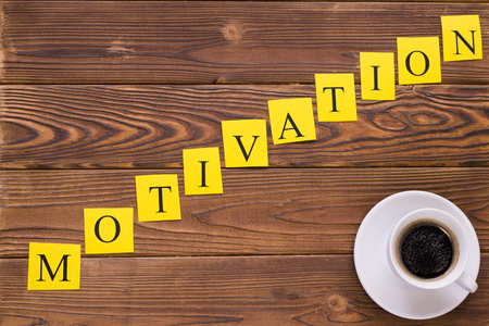 Motivation diagonal inscription of letters printed on yellow papers and a cup of hot espresso.の写真素材