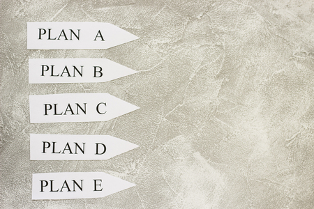 Paper arrows with plan words on a light concrete background. Business and motivation concept. Space for your text or product display.の写真素材