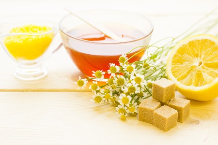 Spa therapy, body care, skin care concept.Camomile flowers, a bowl of honey, a bowl of camomile bath salt, a lemon and brown sugar cubes, close up. A space for your text or product display.の写真素材