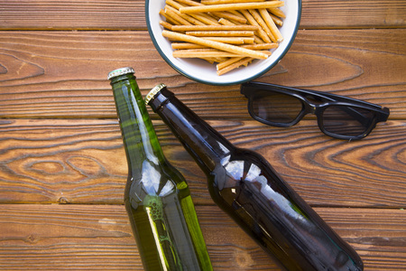 Weekend evening for cople of two friends. A bowl of bread sticks,glasses and two bottles of lager and  beer on a rustic wooden table. Space for your inscription or image.の写真素材