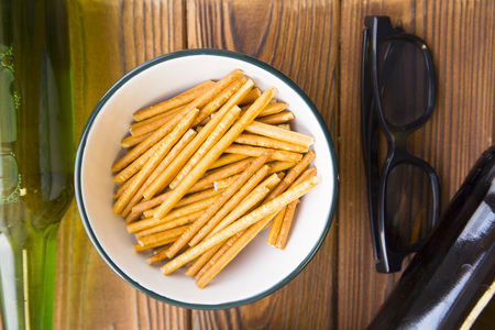 Spend an evening relaxing and watching TV. A bowl of salty breadsticks , two bottles of beer and black glasses on a rustic wooden table.Hobby, leisure conceptの写真素材