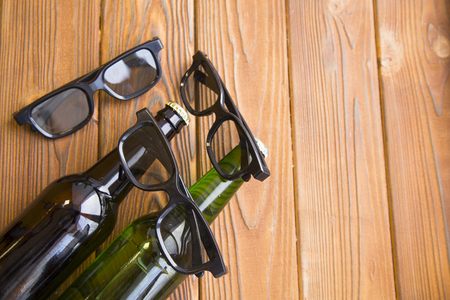 Relax and enjoy a movie with friends. Weekend, hobby and leisure concept. Two bottles of lager and stout beer and three pairs of glasses on a rustic wooden table. Close upの写真素材