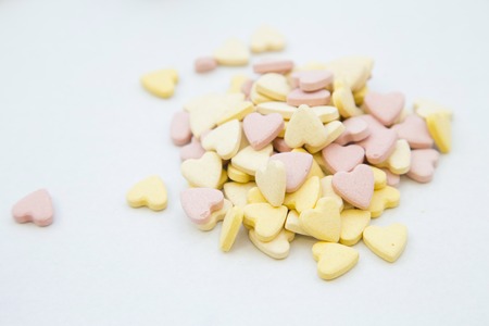 Veterinary and pet healthcare concept. A white background with a pile of yellow and pink heart-shaped pills. Space for your text or image.の写真素材