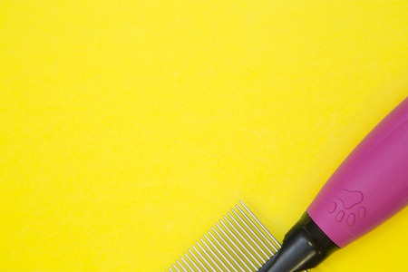 Grooming concept yellow background with a part of steel pet brush. Space for your text or product display.の写真素材