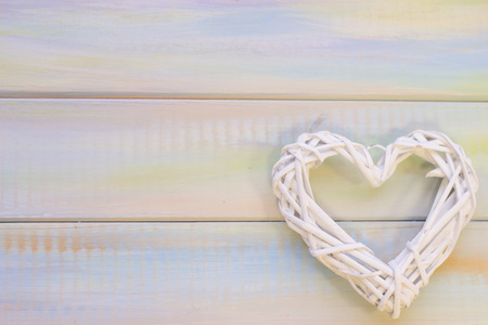 Light colored wooden background with white rattan woven heart. Top view. Space for your inscription or product display. St. Valentine's concept.の写真素材