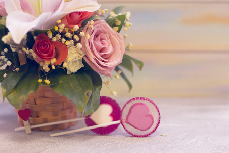 A delicate floral composition in a basket and lolipop candies with hearts. St. Valentines, anniversary, wedding concept with copy space. Space for your text or product display.の写真素材