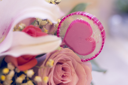 A close up of a pink rose and a lolipop candy with a heart. St. Valentines, anniversary, wedding concept with copy space. Space for your text or product display.の写真素材