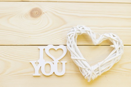 I love you inscription and woven heart wreath on wooden background, close up, top view. Concept of St.Valentine's Day, anniversary, weddingの写真素材