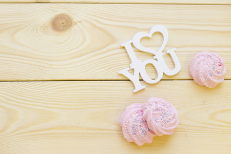 I love you inscription and soft pink marshmellows on wooden background, close up, top view. Concept of St.Valentine's Day, anniversary, weddingの写真素材