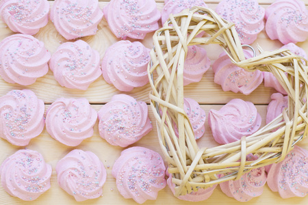 Pink marshmellows for Valentine's Day with a woven heart on a wooden boad, top viewの写真素材
