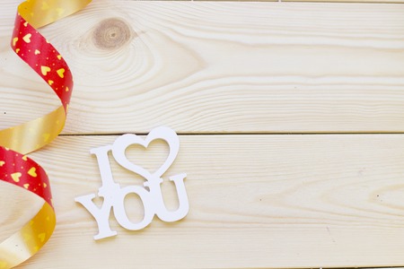 I love you inscription and a red ribbon on a light wooden background, top view. Concept of St.Valentine's Day, anniversary, weddingの写真素材