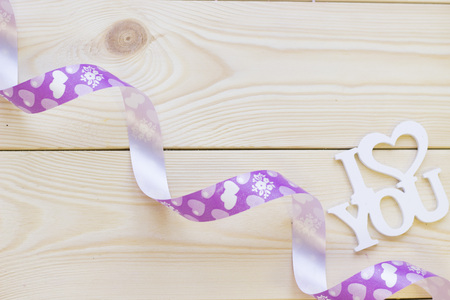 I love you inscription and a purple ribbon on a light wooden background, top view. Concept of St.Valentine's Day, anniversary, weddingの写真素材
