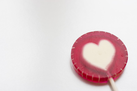 Valentine's concept with a lolipop candy with a heart white background, close upの写真素材
