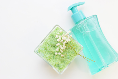 Natural green cosmetics concept. Fragrant bath sea salt and a blue liquid soap bottle with dispenser, white background, top viewの写真素材