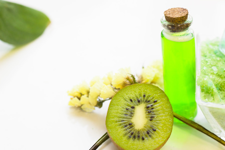 Fruit aromatherapy concept with essential oil in bottles and kiwi, white background, close up