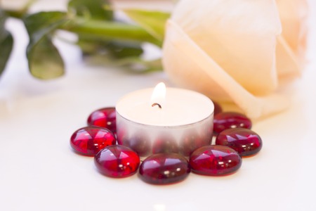 St. Valentine's Day concept with a beautiful cream rose and burning candle, close up, white backgroundの写真素材