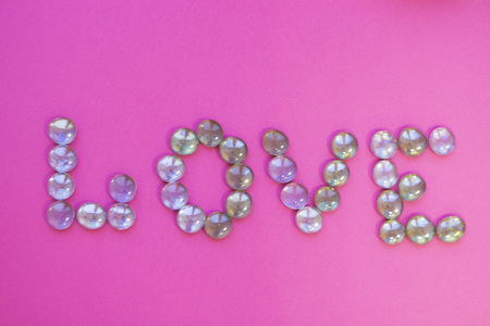St. Valentine's Day or Anniversary concept Love letters made of glass pebbles, pink background,...