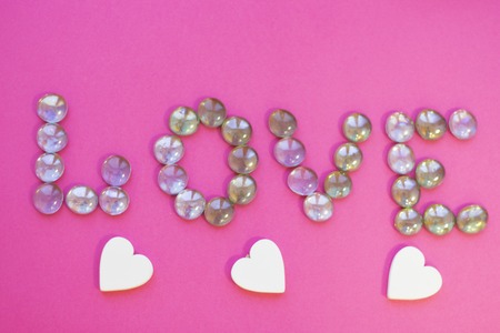 St. Valentine's Day or Anniversary concept Love letters made of glass pebbles, pink background, close up, top viewの写真素材
