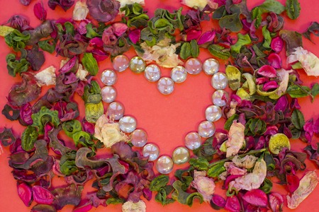 The concept of St.Valentine's Day, red background with a frame of rose petals and glass pebbles and...