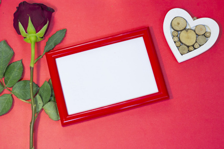 The concept of St.Valentine's Day red background with a beautiful red rose and a red photo frame, top view, copy spaceの写真素材
