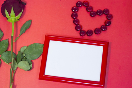The concept of St.Valentine's Day red background with a beautiful red rose and a red photo frame, top view, copy spaceの写真素材
