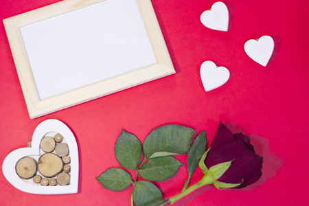 The concept of St.Valentine's Day with a beautiful red rose and wooden photo frame, red background, top viewの写真素材