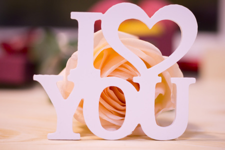 Concept of St.Valentine's Day, Love, Anniversary, Wedding with I love you inscription and a beautiful cream rose in a close up, light blurred backgroundの写真素材