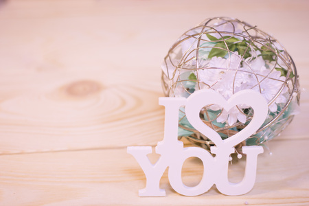 Concept of St.Valentine's Day, Love, Anniversary, Wedding with I love you inscription and a decoration with flowers in a close up, light blurred backgroundの写真素材