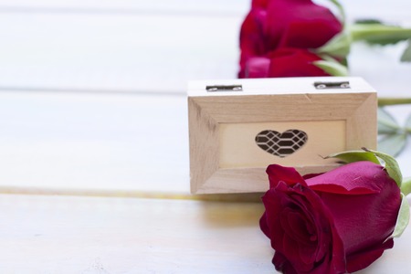The concept of Love, Wedding, Proposal, Anniversary, St. Valentine's Day, Mother's Day with beautiful red velvet roses and decorative wooden casket in a close up, light wooden backgroundの写真素材