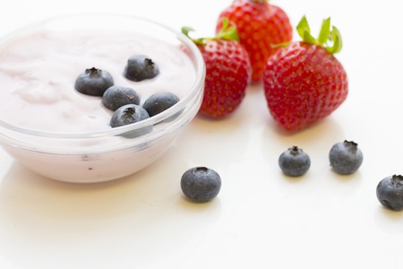 Healthy Breakfast Concept with a bowl of fresh homemade youghurt with blueberries and strawberries on white, close up, copy spaceの写真素材