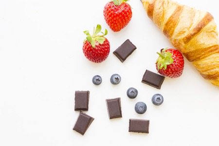 Healthy Breakfast Concept: fresh croissant, blueberries, strawberries and chocolate on white, top view mock upの写真素材