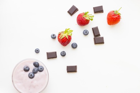 Healthy Breakfast Concept: fresh homemade youghurt, blueberries, strawberries and chocolate on white, top view mock upの写真素材