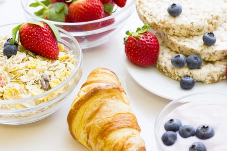 Healthy Delicious Breakfast Concept: a french croissant, a bowl of strawberries, wheat breadcrisps...