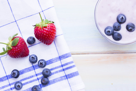 Romantic French or Rural Breakfast with a bowl of homemade youghurt with blueberries and strawberries. Napkin and wood as a background, top viewの写真素材