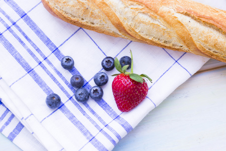 Romantic French or Rural Breakfast with a baguette and fresh blueberries and strawberry. Napkin and wood as a background, top viewの写真素材