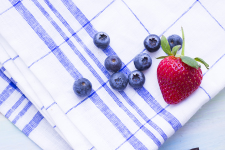Romantic French or Rural Dessert Concept: a close up of fresh blueberries and strawberry. Napkin and wood as a background, top viewの写真素材