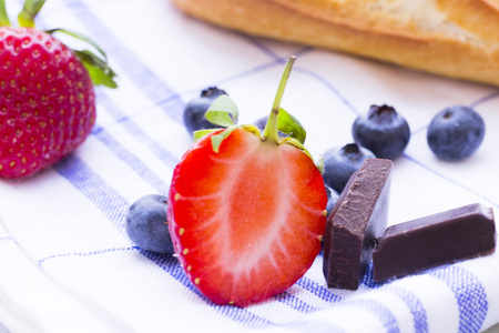 Dessert, Breakfast Ingredients concept with a baguette, fresh blueberries and strawberry and chocolate. Napkin and wood as a background, close upの写真素材