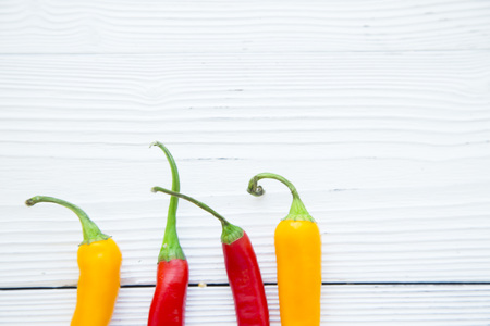 Cooking, Vegetarian, Vegan Concept.A white wooden background with red and yellow chili peppers with...