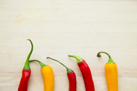 Cooking, Vegetarian, Vegan Concept.A light wooden background with red and yellow chili peppers with...