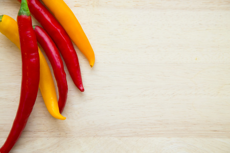 Cooking, Vegetarian, Vegan Concept.A light wooden background with red and yellow chili peppers with...