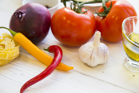 Preparing Healthy Food, Vegeterian, Vegan Concept. A close up of tomatoes, red onion, chili peppers and garlic on a white wooden table, close upの写真素材