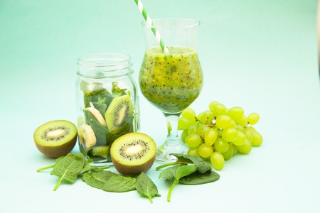 Fresh homemade green smoothie with kiwi, grape, banana and spinach on a light blue background. Diet, Fitness, Dessert Conceptの写真素材
