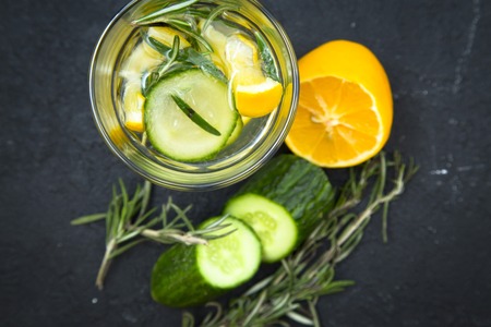 Glass jar of detox water with lemon, cucumber and a spring of rosemary and ingredients on the table, black stone background, top viewの写真素材