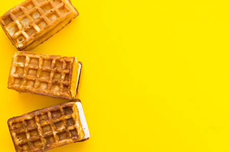 Delicious breakfast: fresh waffles on a yellow background with copy space, top view
